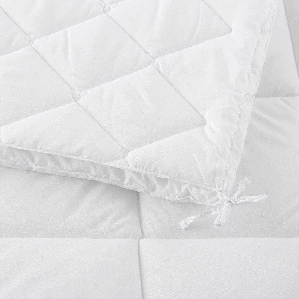 Un primer plano de un edredón blanco sobre una cama.