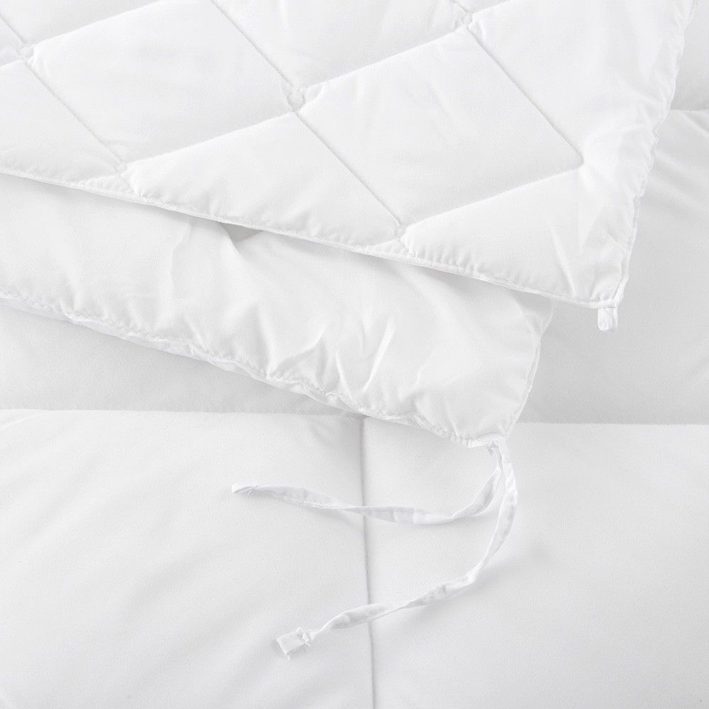 Un primer plano de un edredón blanco sobre una cama.