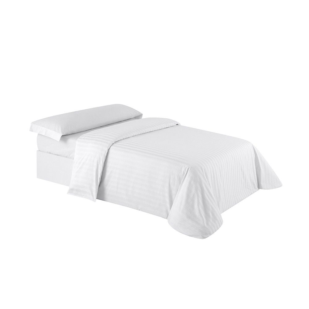Una cama con un edredón blanco y almohadas encima.