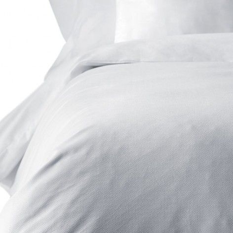 Un primer plano de un edredón blanco y almohadas en una cama.