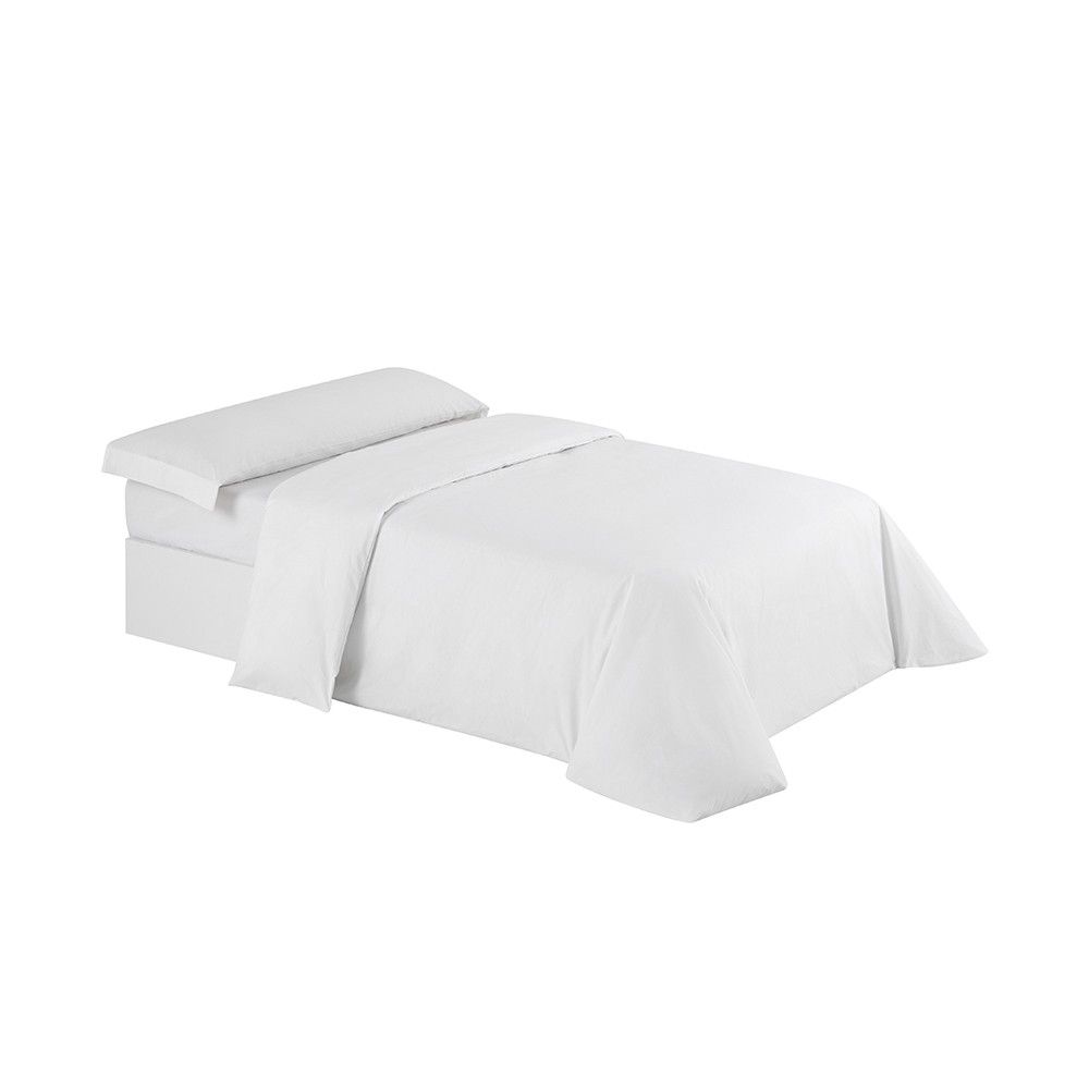 Una cama con un edredón blanco y almohadas encima.