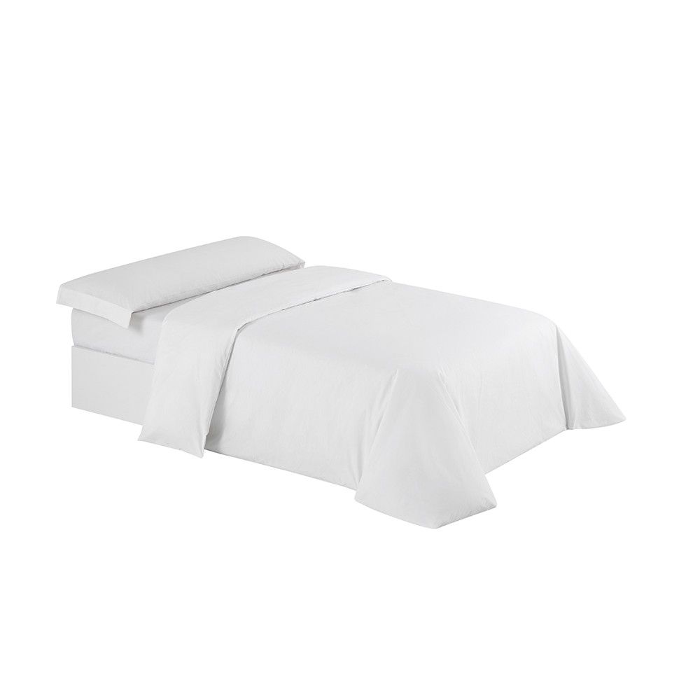 Una cama con un edredón blanco y almohadas encima.