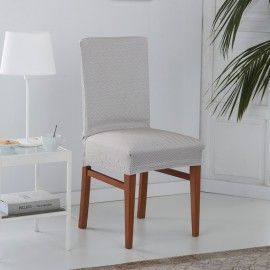 Una silla está sentada en una sala de estar al lado de una lámpara y una mesa.