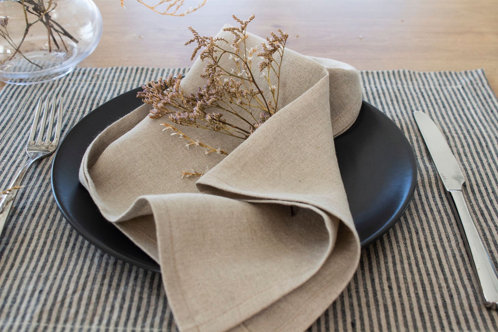 Una servilleta está sobre un plato negro sobre una mesa.