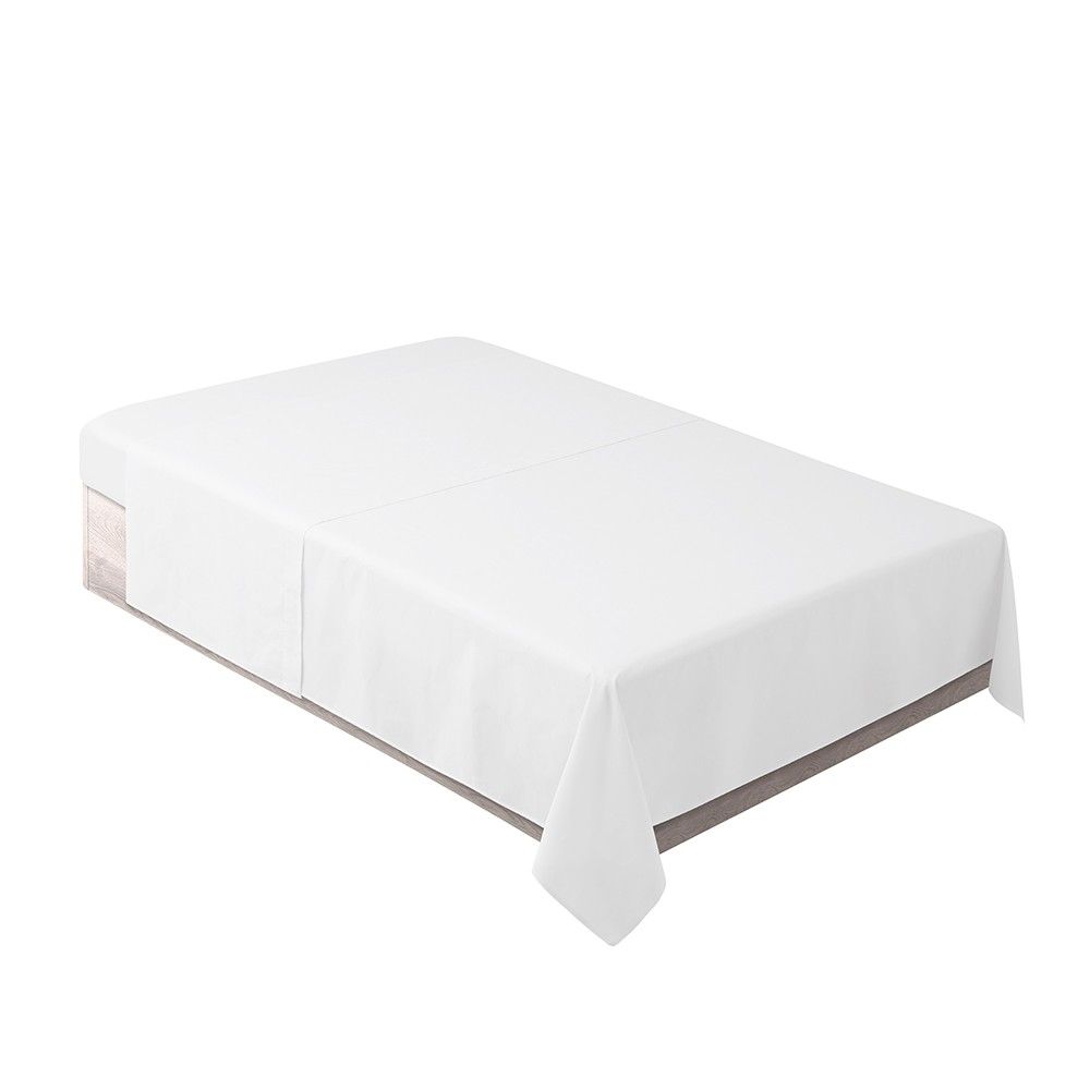 Una cama con un mantel blanco encima.