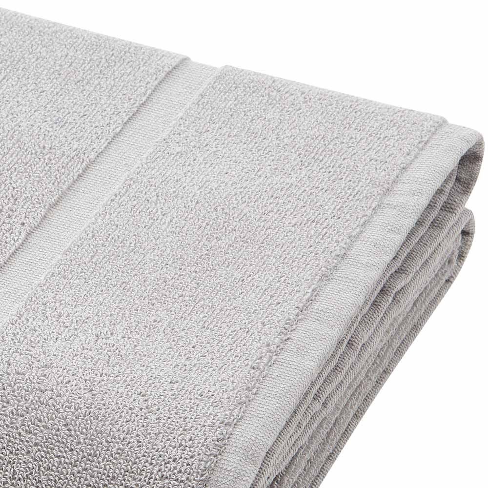 Toalla gris claro doblada con superficie texturizada y detalle de borde.