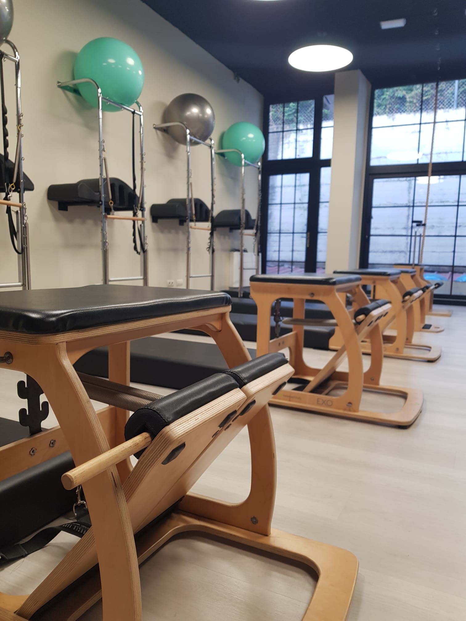 Estudio de ejercicios con máquinas de Pilates reformer, espejos y pelotas de ejercicio.