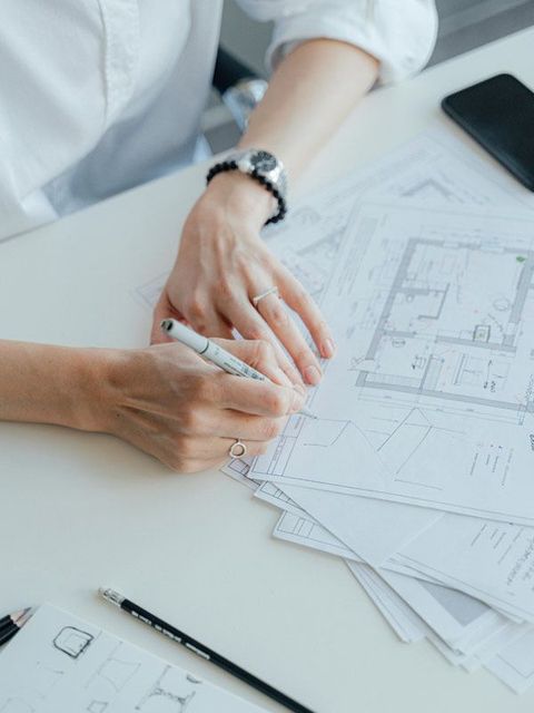 Una mujer está sentada en una mesa escribiendo en un trozo de papel.