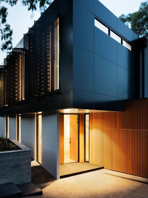 Una casa moderna con fachada negra y puerta de madera.