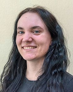 Eine Frau mit langen schwarzen Haaren lächelt in die Kamera.