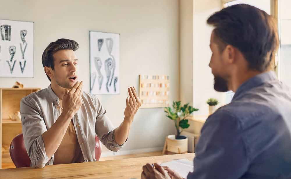 Zwei Männer sitzen an einem Tisch und unterhalten sich.