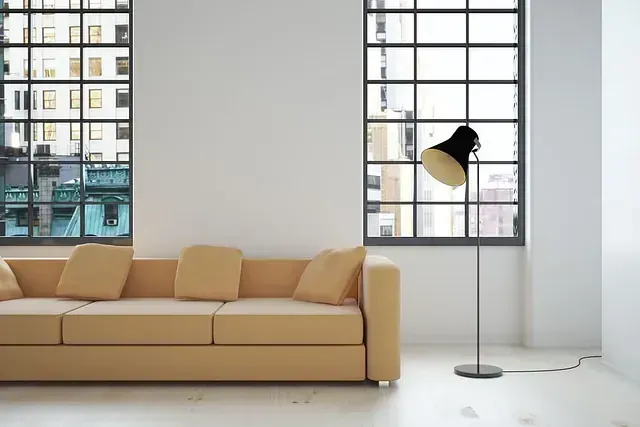 Una sala de estar moderna con un sofá color canela, una lámpara negra y grandes ventanales con vistas a la ciudad.