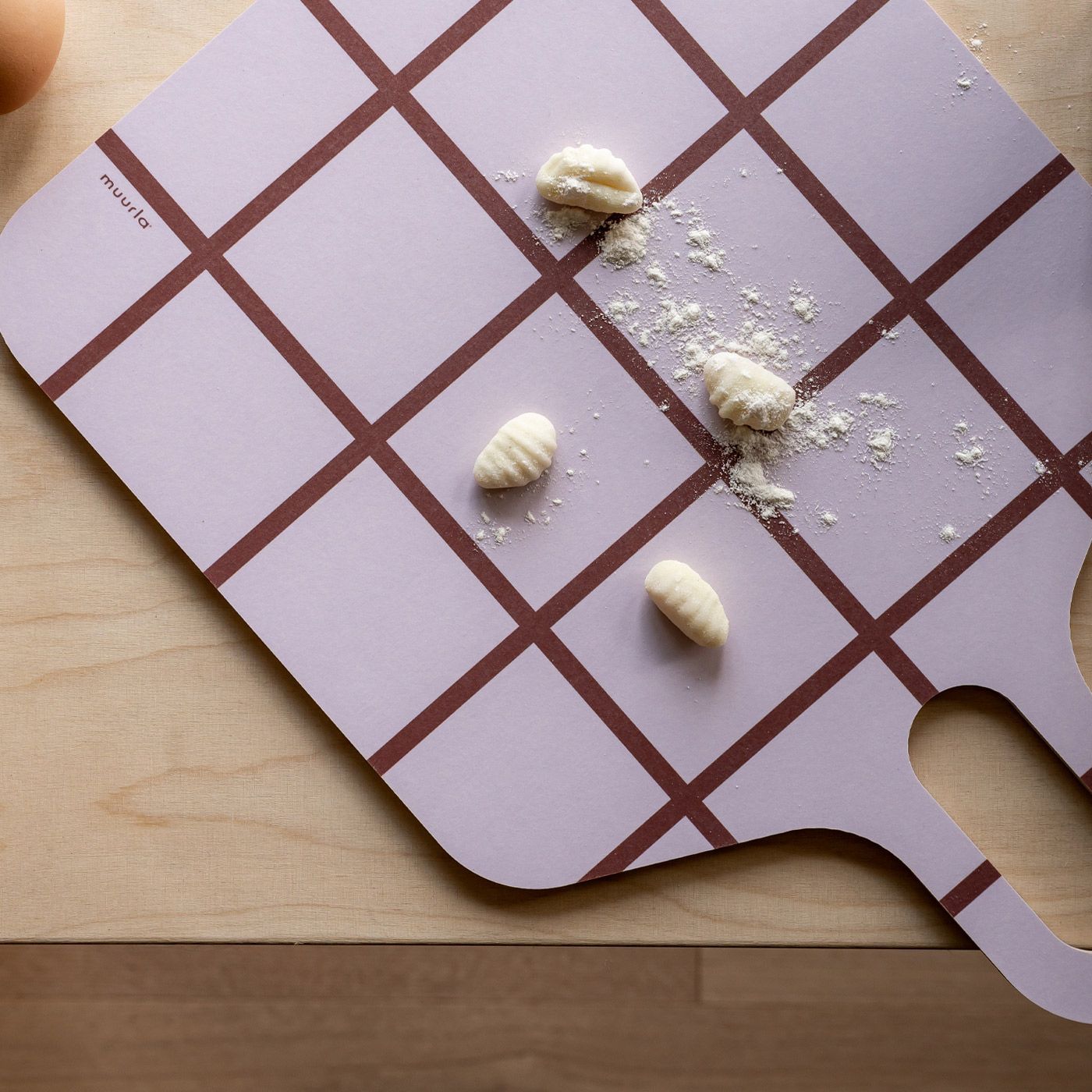 Neljä gnocchia ja jauhoja vaaleanliilalla, kuvioidulla tarjottimella.