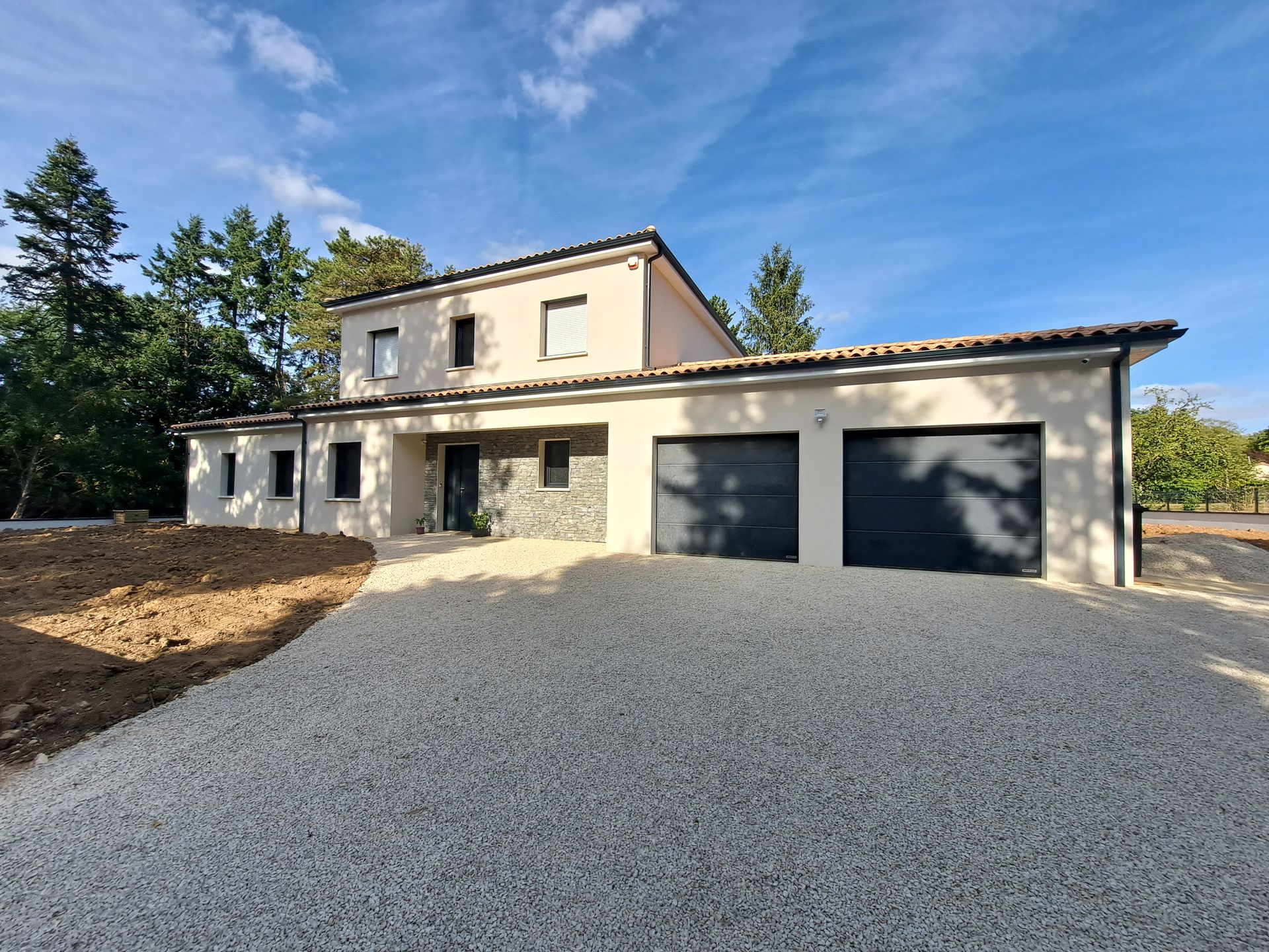 Maison neuve avec de nombreuses ouvertures et deux portes de garage gris anthracite