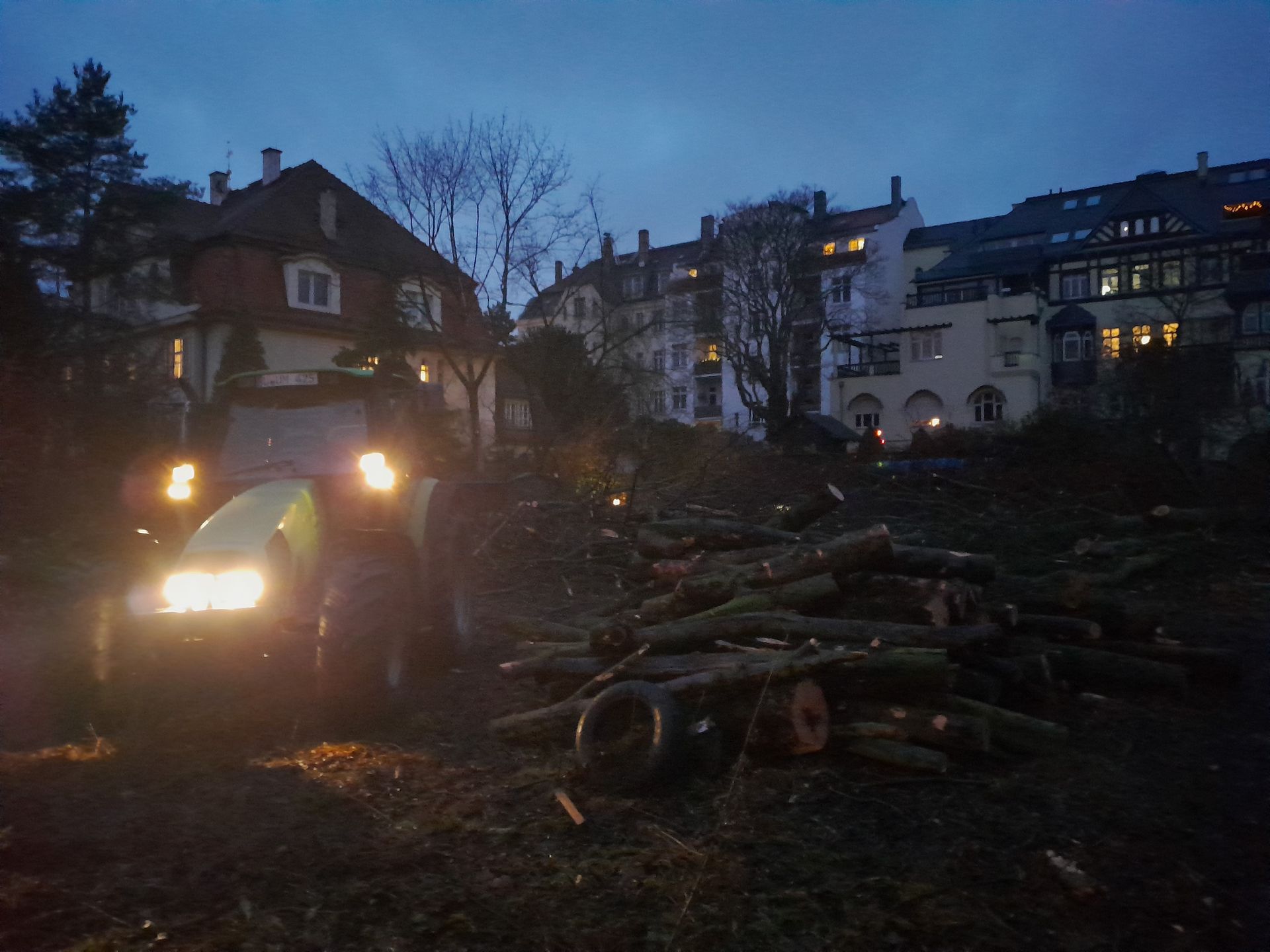 Ein Traktor fährt nachts durch einen Stapel Baumstämme.
