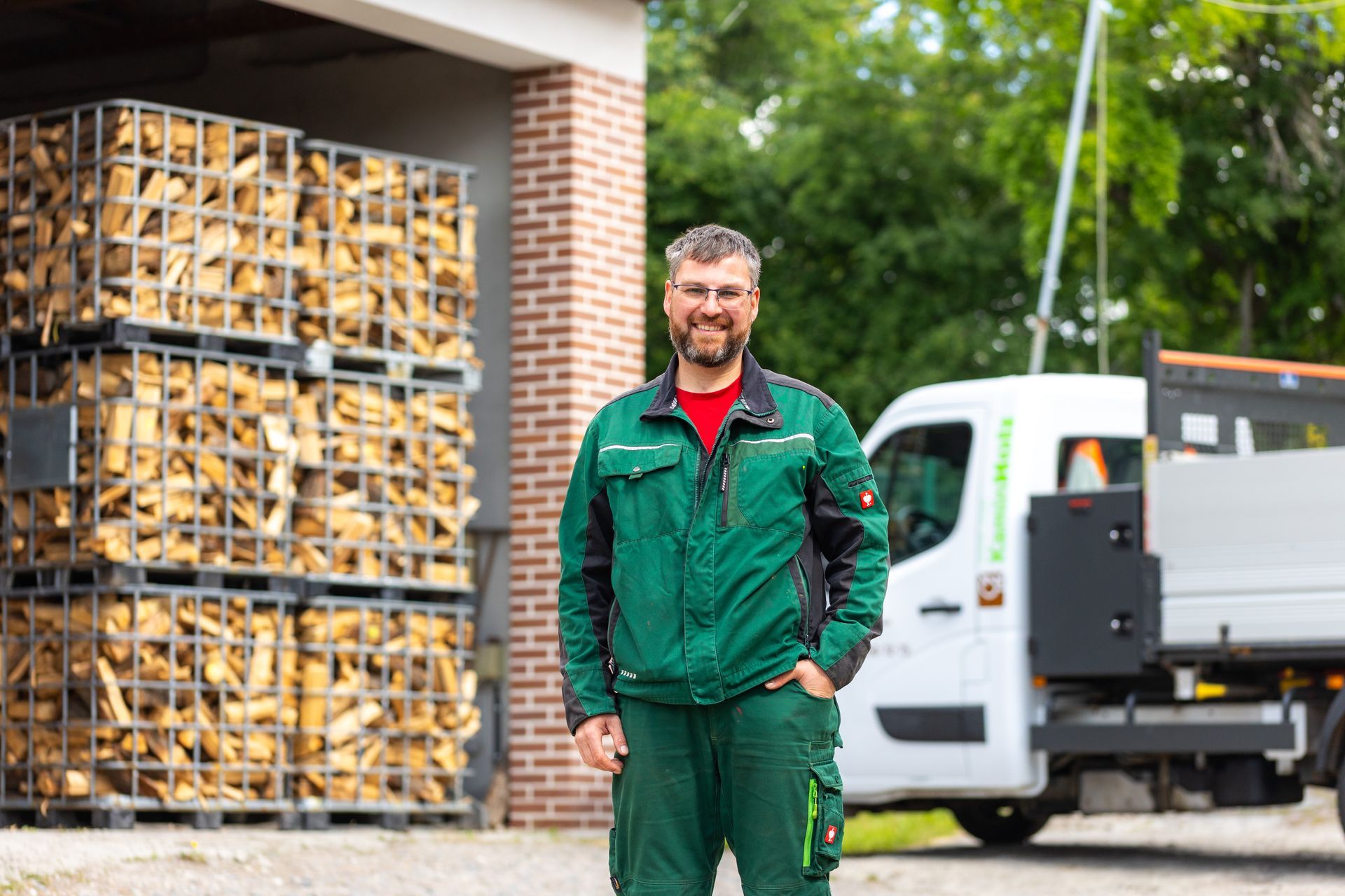 Ein Mann in einer grünen Jacke steht vor einem Lastwagen.