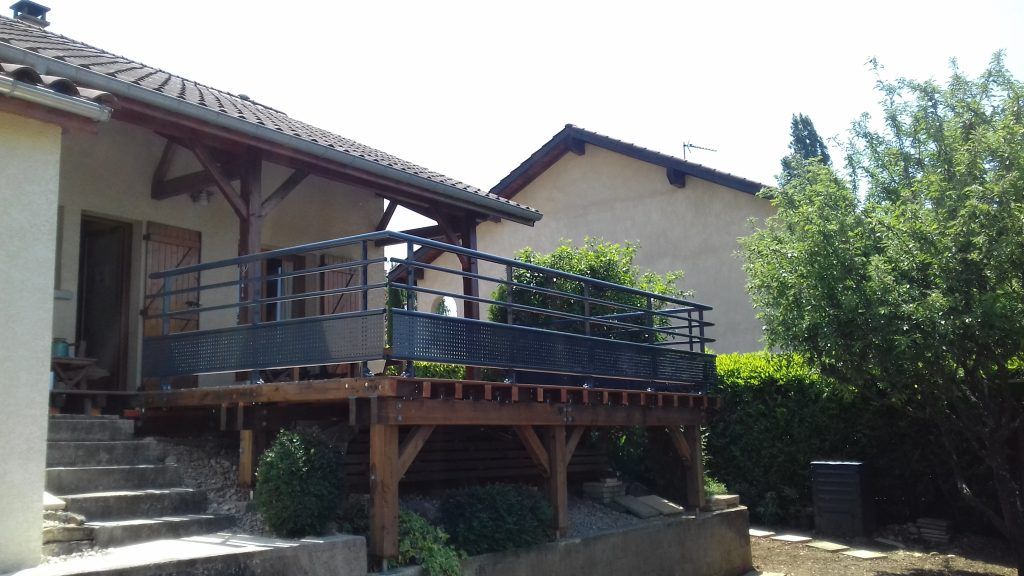 Maison avec terrasse et balustrade en métal noir.