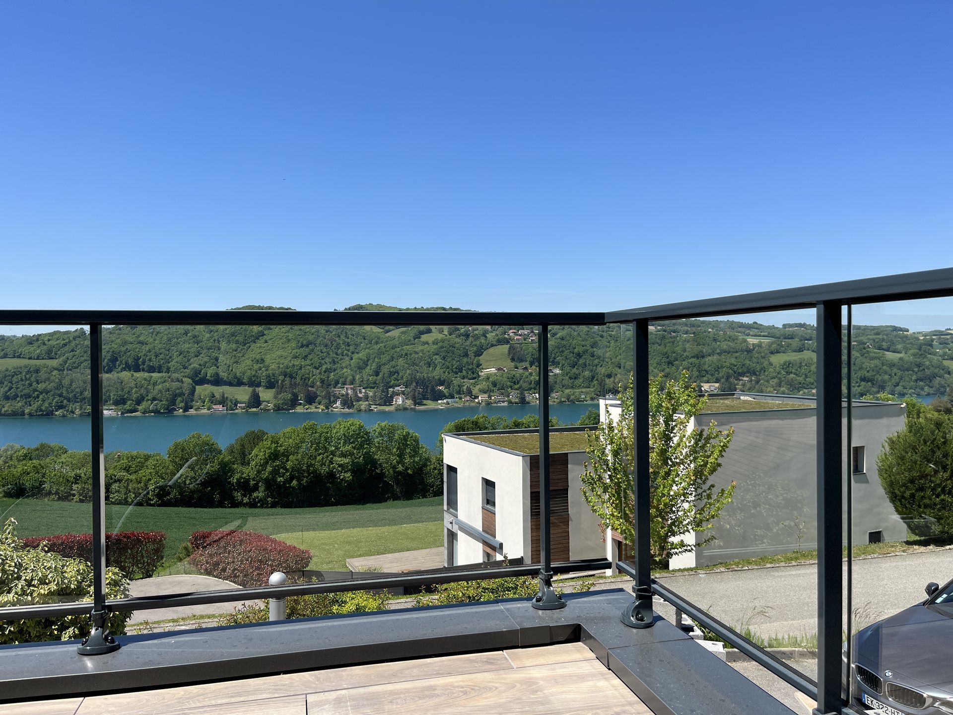 Vue à travers un garde-corps vitré, depuis le balcon sur un lac.