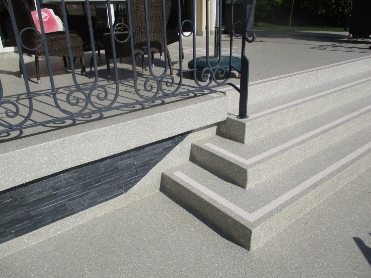 Des marches en résine longent une balustrade en métal noir.