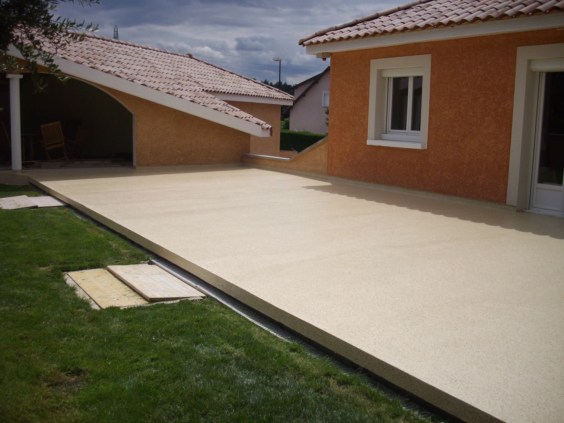Allée en résine longeant des maisons en stuc orange.