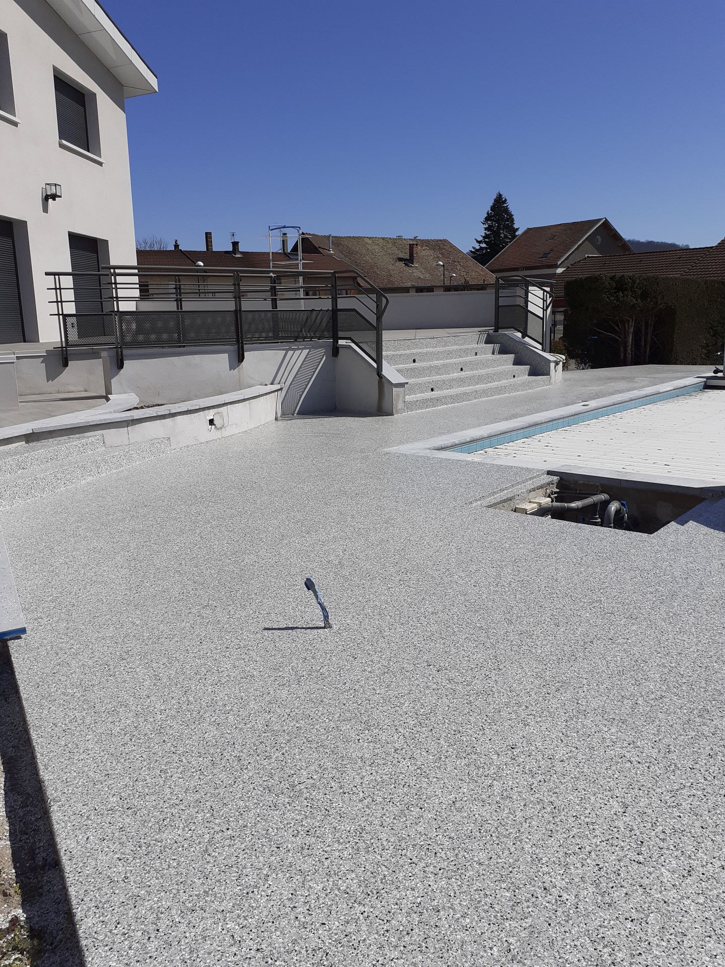 Jardin avec terrasse de piscine en résine.