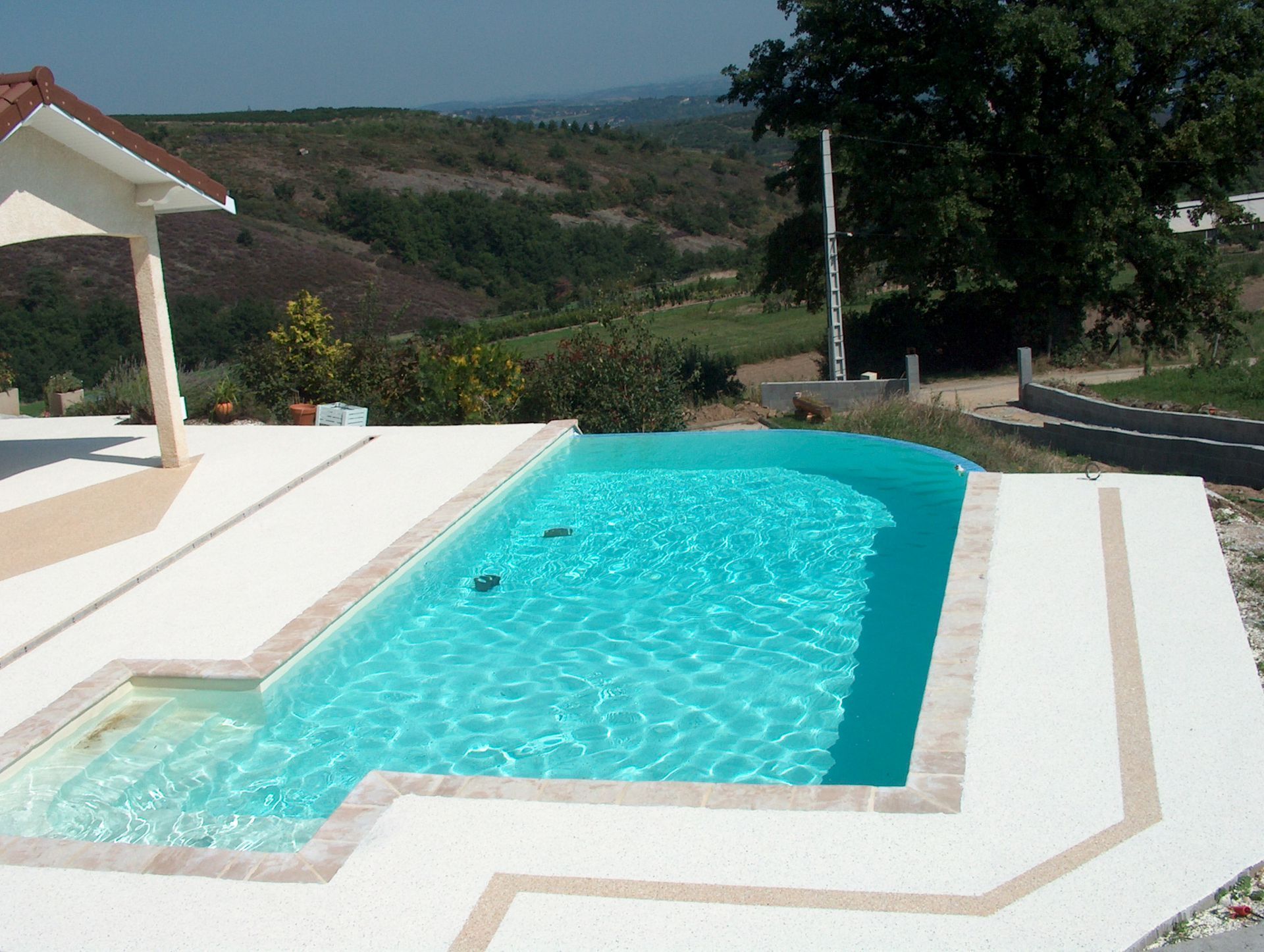 Piscine extérieure aux eaux turquoise bordée d'une plage en résine.
