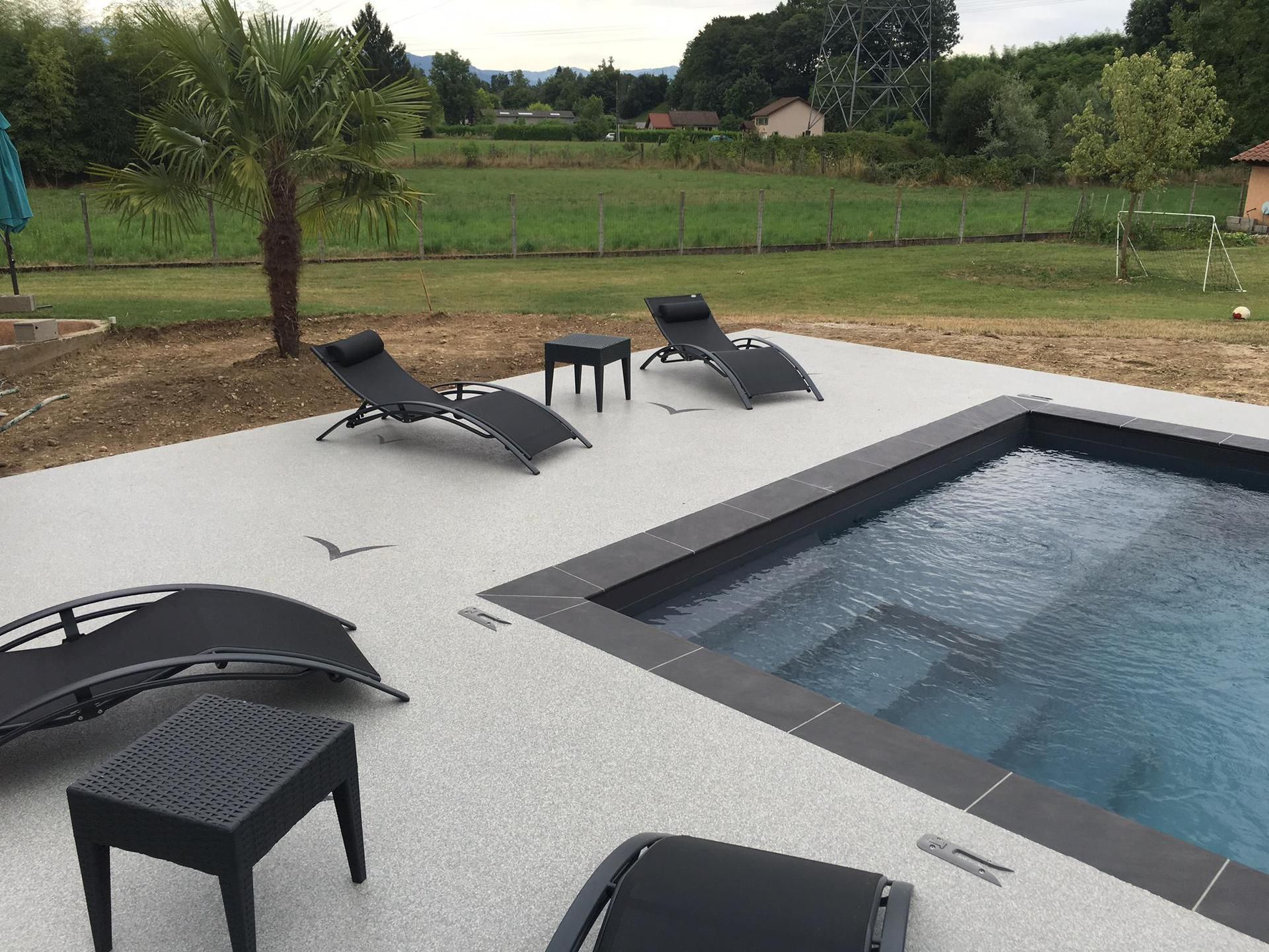 Terrasse de piscine moderne avec terrasse en résine grise.