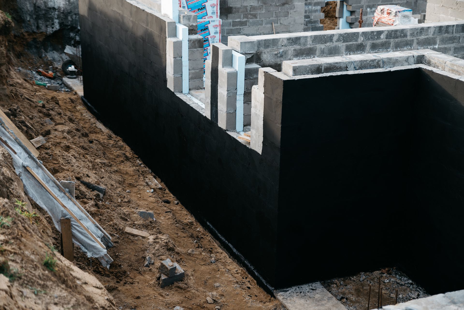 Tranchée de fondation avec parois noires étanches.