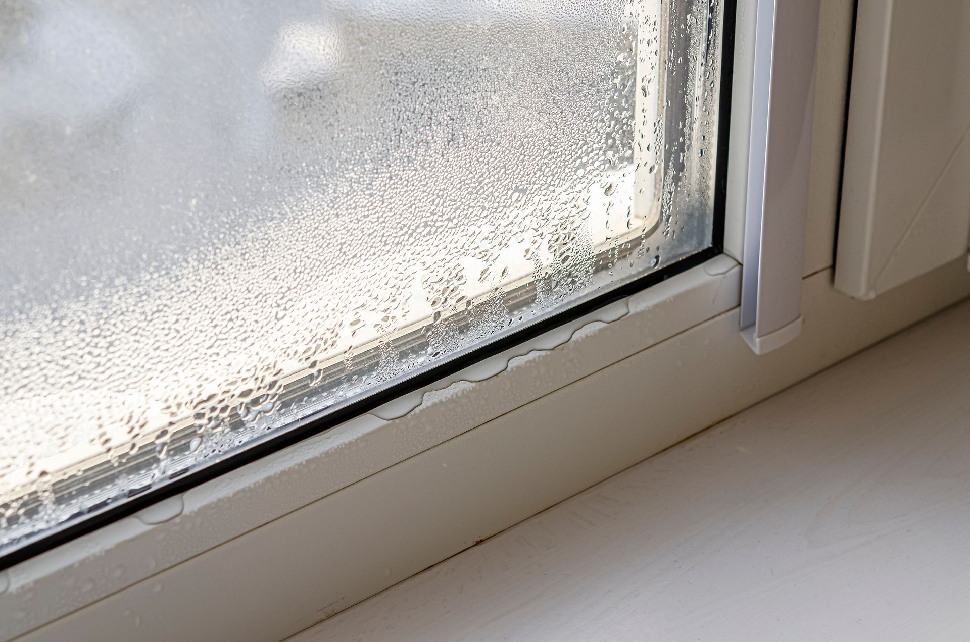 Fenêtre embuée par la condensation et appui de fenêtre blanc à l'intérieur.