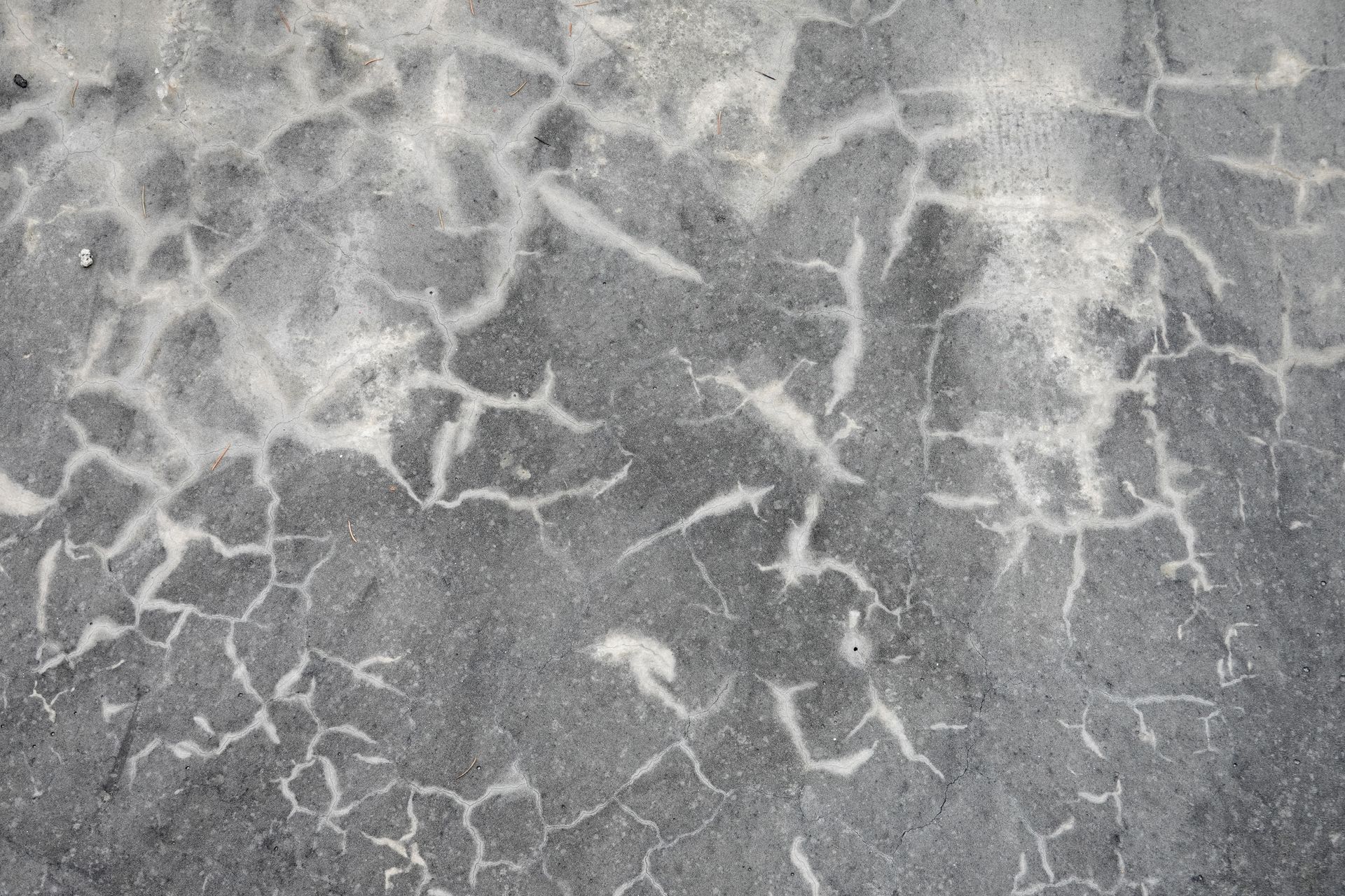 Surface en béton ou en pierre grise fissurée.
