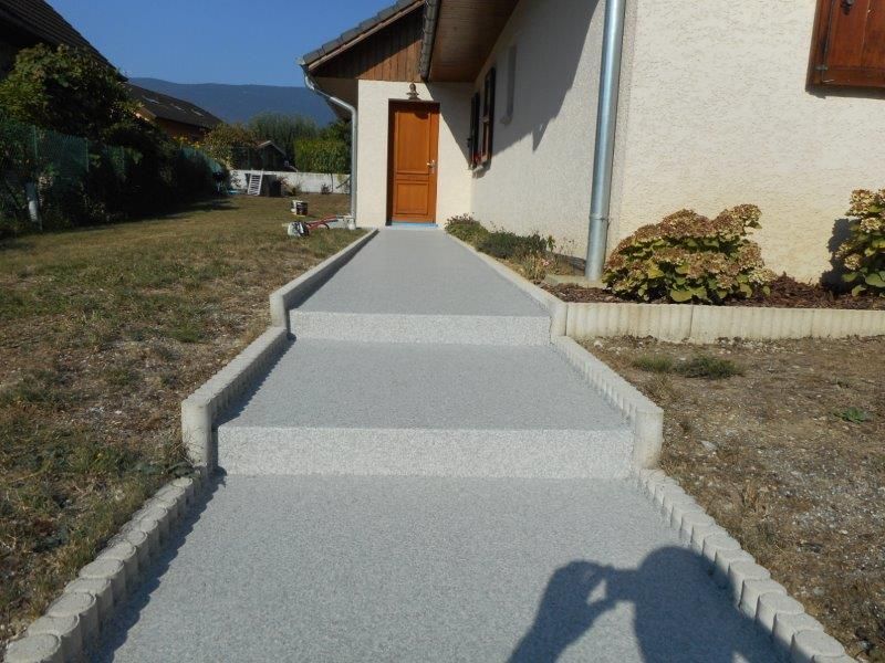 Allée en résine menant vers une porte d'entrée.
