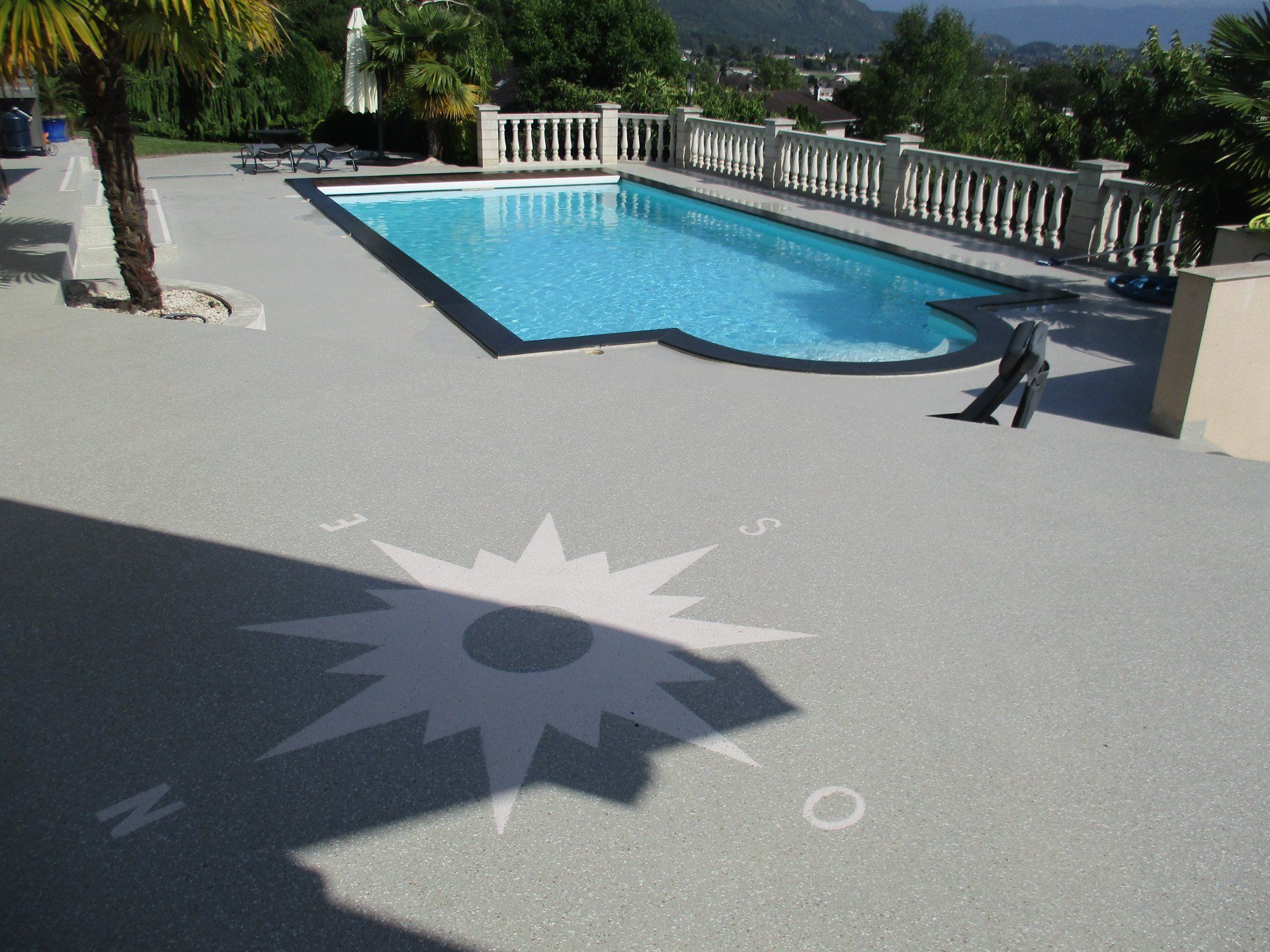Terrasse en résine bordant une piscine.