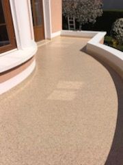 Allée extérieure incurvée en résine beige.