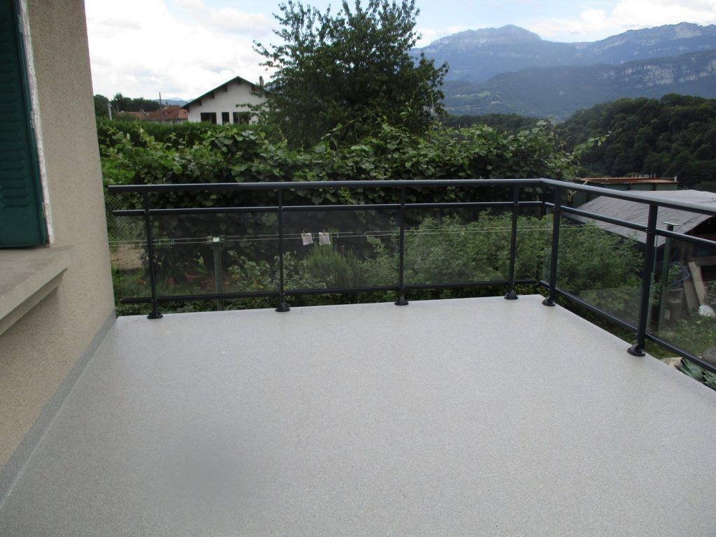 Balcon en résine avec rambarde noire donnant sur des collines et des montagnes verdoyantes