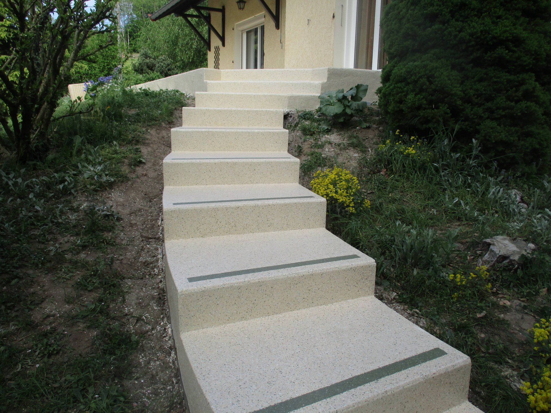 Un escalier extérieur en résine bordé par de la végétation.