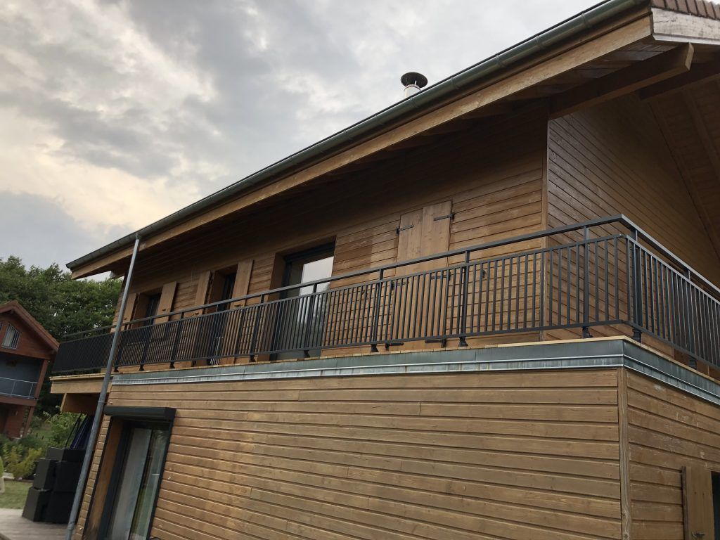 Bâtiment avec une balustrade noire sur un toit en pente sous un ciel nuageux