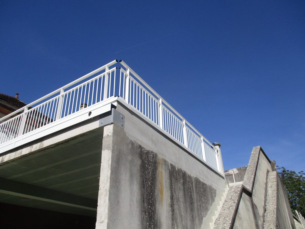 Rambarde blanche au sommet d'un pont en béton se détachant sur un ciel bleu clair