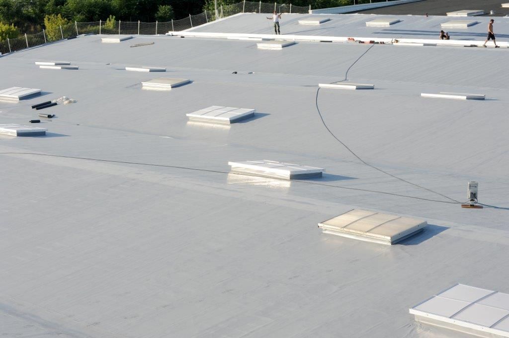 Toit plat recouvert d'une membrane blanche et percé de quelques ouvertures de ventilation.