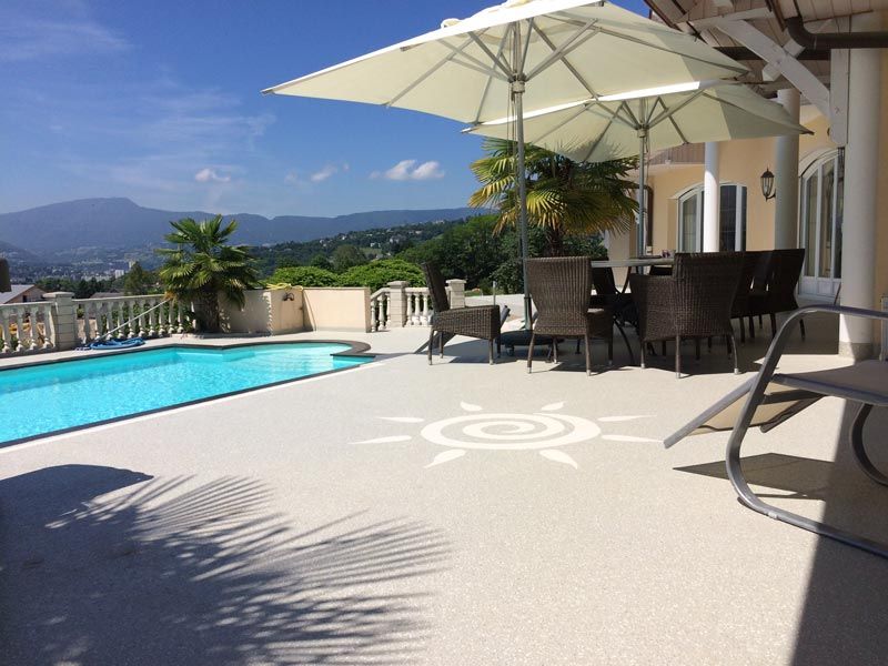 Terrasse en ésine avec motif de soleil en bord de piscine.