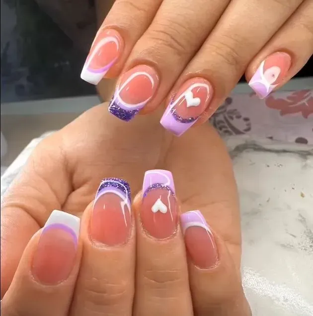 Un primer plano de las uñas de una mujer con un corazón en ellas.