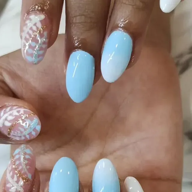 Un primer plano de la mano de una persona con uñas azules y blancas.