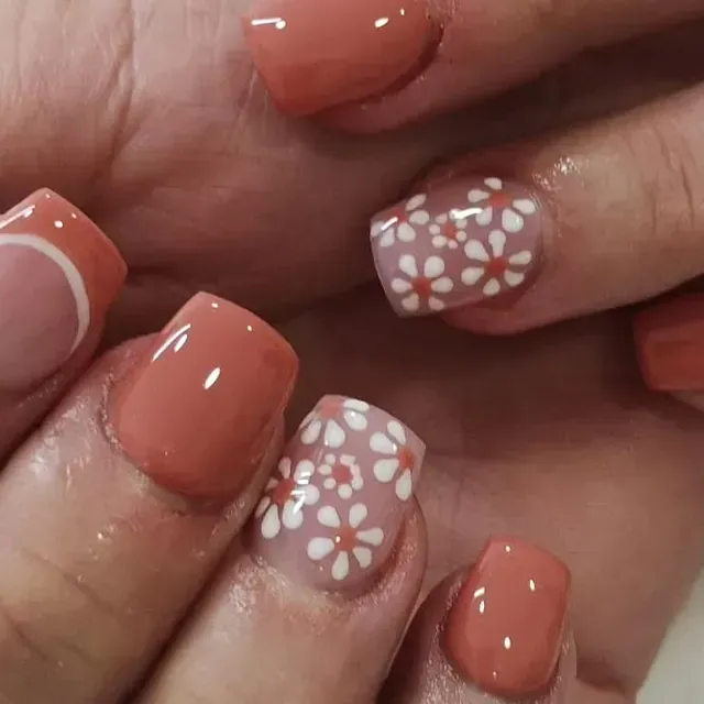 Un primer plano de las uñas de una persona con flores en ellas.