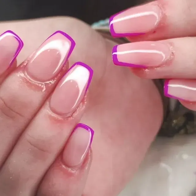 Un primer plano de las uñas de una mujer con una manicura francesa morada.