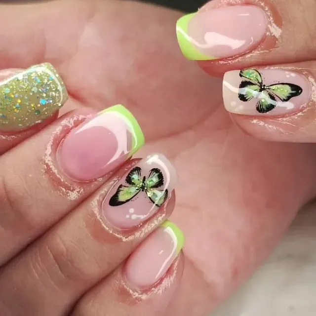 Un primer plano de las uñas de una mujer con un diseño de mariposa.