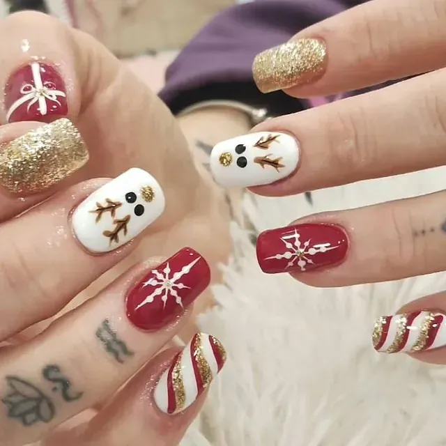 Las uñas de una mujer están decoradas con muñecos de nieve y copos de nieve.
