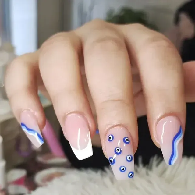 Un primer plano de las uñas de una mujer con diseño de mal de ojo.