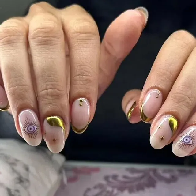 Un primer plano de las uñas de una mujer con un diseño de mal de ojo.