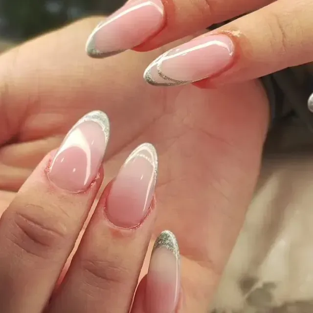 Un primer plano de la mano de una mujer con uñas rosas y blancas.