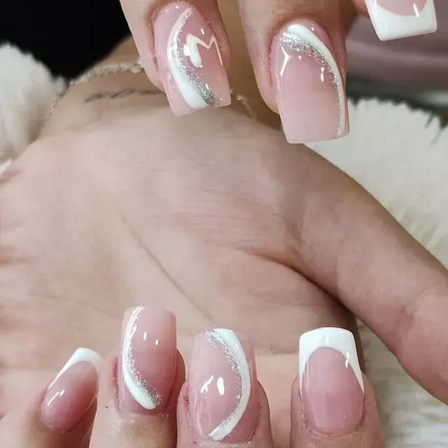 Un primer plano de las uñas de una mujer con manicura francesa.
