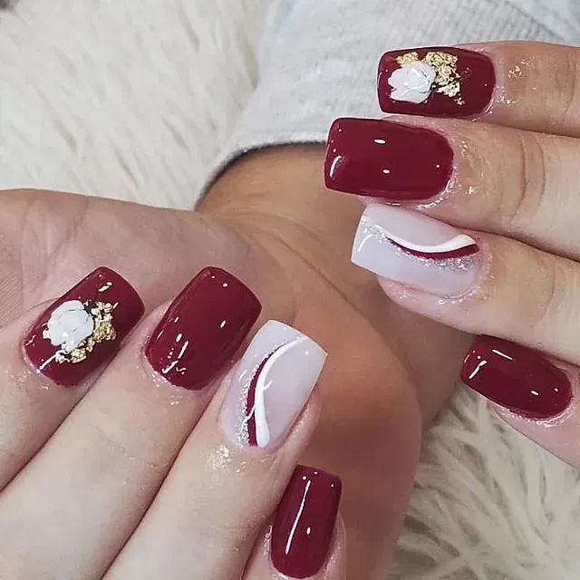 Un primer plano de la mano de una mujer con uñas rojas y blancas.